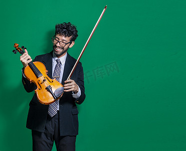 微笑的小提琴家看着相机，拿着小提琴，孤立背景下的小提琴家概念，孤立的微笑小提琴家的肖像