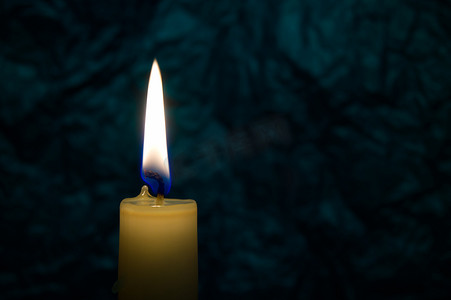黄色蜡烛光摄影照片_单独燃烧在黑暗中的唯一黄色蜡蜡烛