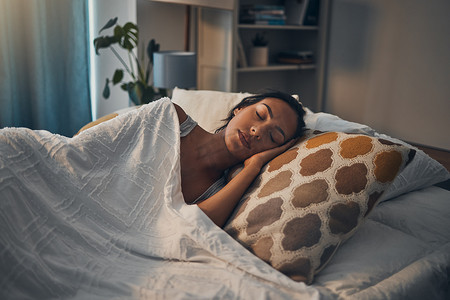 一个美丽的年轻混血女人睡在家里柔软舒适的床上。