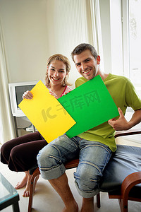 夫妇坐在家里拿着彩色海报