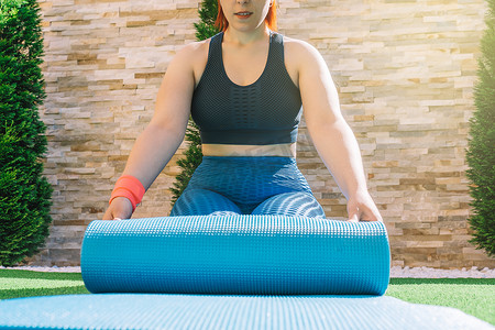 一位年轻健身女性的裁剪镜头，伸展瑜伽垫练习放松练习。