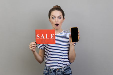 女人张着嘴站着，拿着销售卡和手机，显示屏空着。