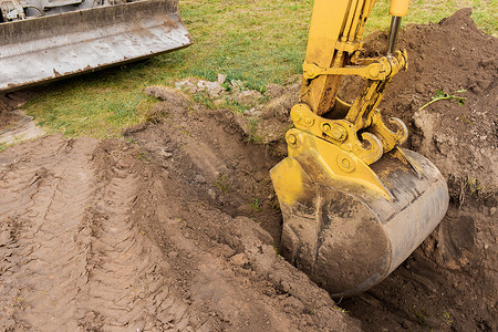 一桶挖掘机用一堆泥土在建筑工地上挖了一个洞。