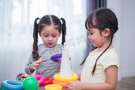 玩球的孩子们摄影照片_两个小女孩一起在家里玩小玩具球。