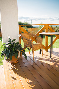 乡间别墅或小屋的舒适木质露台享有花园景观 — 桌椅可供放松的夜晚