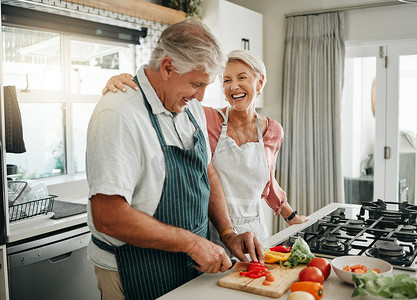老夫妇一边做饭一边享受乐趣，同时在家里的厨房准备健康的蔬菜食品和素食餐，一边欢笑一边享受乐趣。