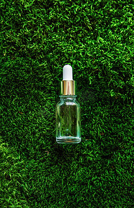 精油熬制摄影照片_瓶子里的化妆品和苔藓上的精油。