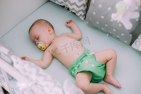 婴儿躺在他的婴儿床里，看着相机。