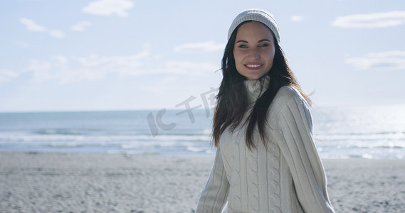 装秋摄影照片_穿着秋装的女孩在海滩上微笑