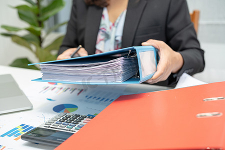 亚洲会计师持有活页夹，并在现代办公、财务和商业概念中使用图表和笔记本电脑分析财务项目会计。