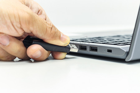 商人之手将 USB 驱动器推入 USB 端口，用于笔记本电脑传输数据或保存数据