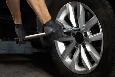 汽车修理工在车库车间更换车轮轮胎。