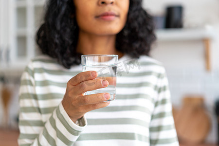 不露面的非洲裔美国女性在厨房里喝一杯水。