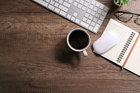 顶视图无线键盘、一杯咖啡和木质背景的笔记本。
