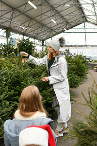 母亲和孩子们摄影照片_母亲和孩子们在商店里选择一棵圣诞诺曼树
