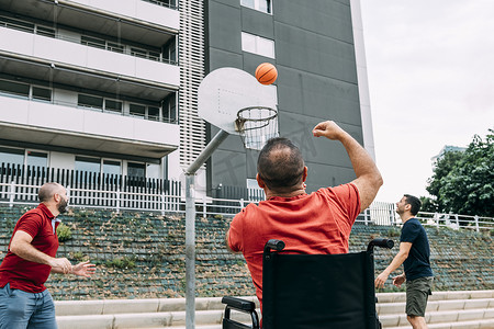 蓝球体育运动摄影照片_残疾人和两个朋友一起扔进篮子