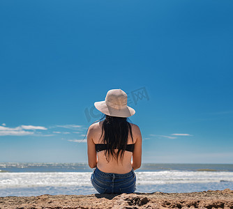女孩望天空摄影照片_戴帽子的女人从背到海，戴帽子的女孩望海，度假概念，看海的女孩的后视图