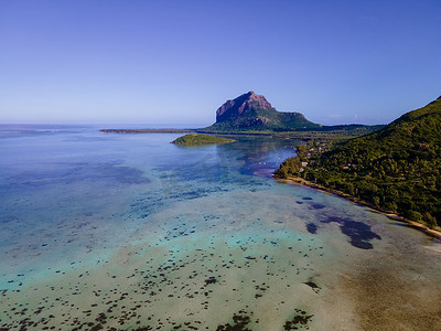 Le Morne 海滩毛里求斯，带棕榈树和白色沙滩蓝色海洋的热带海滩和带雨伞的沙滩床、太阳椅和遮阳伞在热带海滩的棕榈树下，Le Morne 海滩毛里求斯