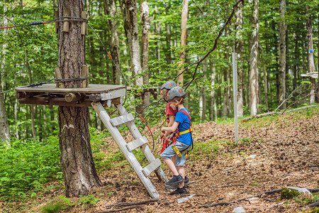 两个戴头盔的男孩，健康的少年男学生，夏日在攀岩冒险公园享受活动