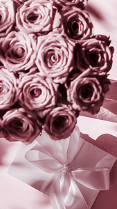 惊喜礼盒摄影照片_豪华假日丝绸礼盒和玫瑰花束，粉红背景、浪漫惊喜和鲜花作为生日或情人节礼物