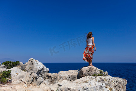 海平线摄影照片_女士站在石崖边，眺望远方的海平线。