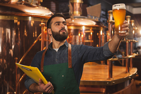 快乐的男性酿酒师在他的精酿啤酒生产中工作