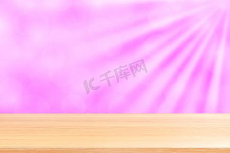 空木桌地板上柔和的粉红色散景灯光束闪耀渐变背景，木板空在粉红色散景彩色灯光上，粉红色彩色散景灯渐变软用于横幅广告