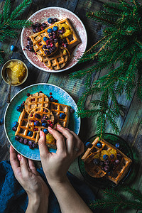 蓝莓酱摄影照片_羊角面包华夫饼或 Croffle 配草莓和蓝莓酱，在盘子和深色背景中供应。