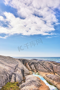南非开普敦坎普斯湾的岩石海岸和海景，蓝天复制空间和背景中的一座山。
