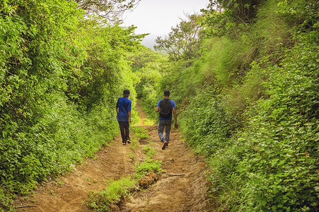 两个男人在穿过乡村的小路上，两个年轻人沿着有复制空间的小路行走