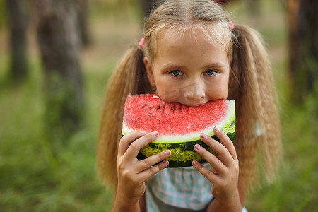 小女孩在花园里吃西瓜。