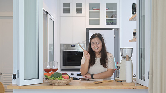 快乐的肥胖亚洲女性准备在家庭厨房制作健康沙拉的配料