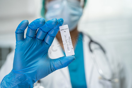 身着 PPE 服的亚洲医生用唾液抗原检测试剂盒在医院检查 Covid-19 冠状病毒时显示阳性检测结果。