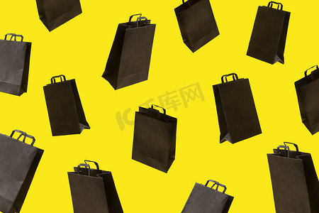 黑色销售购物袋的图案在黄色背景上飞行。
