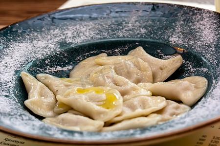 手工煮饺子摄影照片_厨房餐桌上大盘子里手工制作的月桂叶煮肉饺子