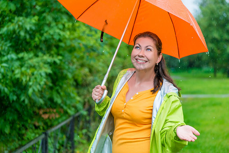 有一把明亮的橙色伞的美丽的女孩