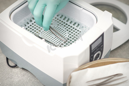 用医疗器械清洁系统对镊子进行手消毒。
