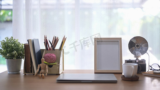 家庭办公桌配有笔记本电脑、盆栽植物、复古相机和咖啡杯。