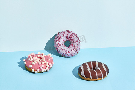 甜甜摄影照片_焦糖和巧克力糖衣的三个甜甜甜甜圈，两种颜色的背景