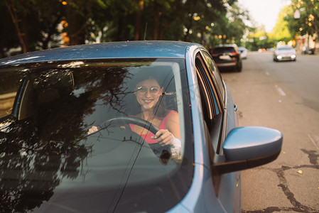 美丽的微笑女人开车，坐在汽车里的女孩