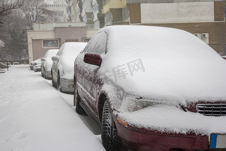 冬日城市街道上被雪覆盖的汽车