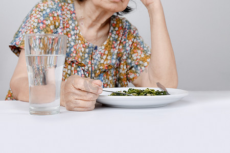 老人生气摄影照片_厌倦食物的亚洲老妇人