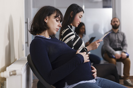 怀孕的招聘人员手牵着肚子在创业公司办公室等待