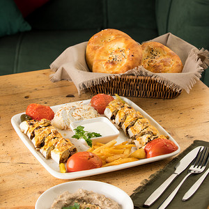 美味的菜肴摄影照片_餐桌上摆满了美味的菜肴和一篮子面包