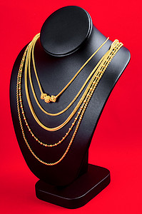 红色天鹅绒织物上带金项链的项链展示架