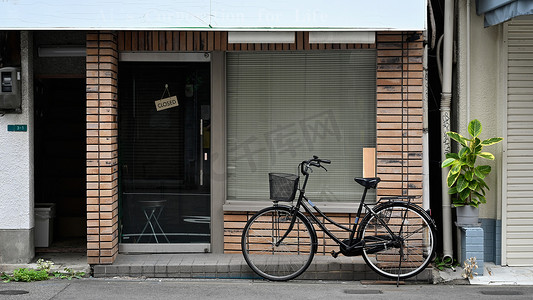 经典咖啡馆砖墙外立面前的城市街道上停着一辆带柳条篮的自行车。