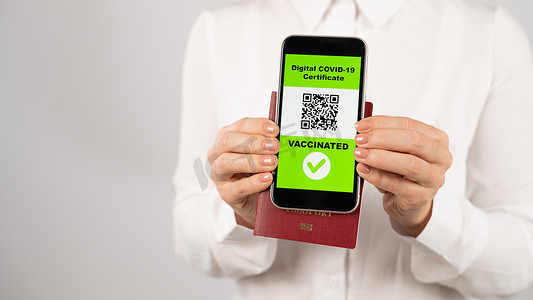 二维码边框几何摄影照片_拿着护照和电话的妇女，上面有关于疫苗接种的二维码。