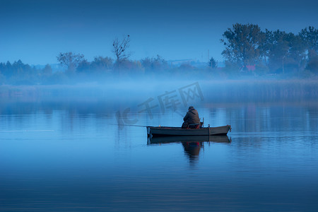 钓鱼者摄影照片_船上的钓鱼者和平静湖面上的雾