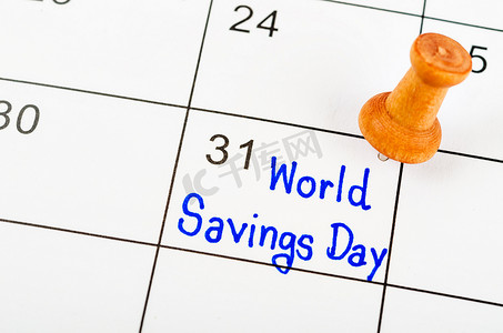 手写的世界储蓄日在白色日历上标有木针。