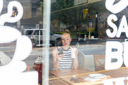 体贴的女人在咖啡店休息时用手机阅读新闻。